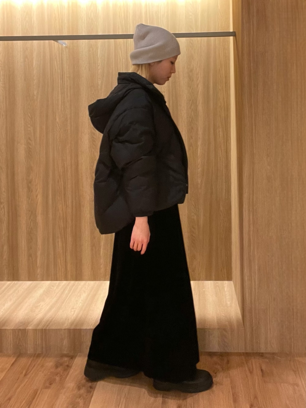 ブラック系のスカート、ブラック系のブーツ、グレー系のハンドバッグを着用したレディースの冬コーディネートの2枚目の写真