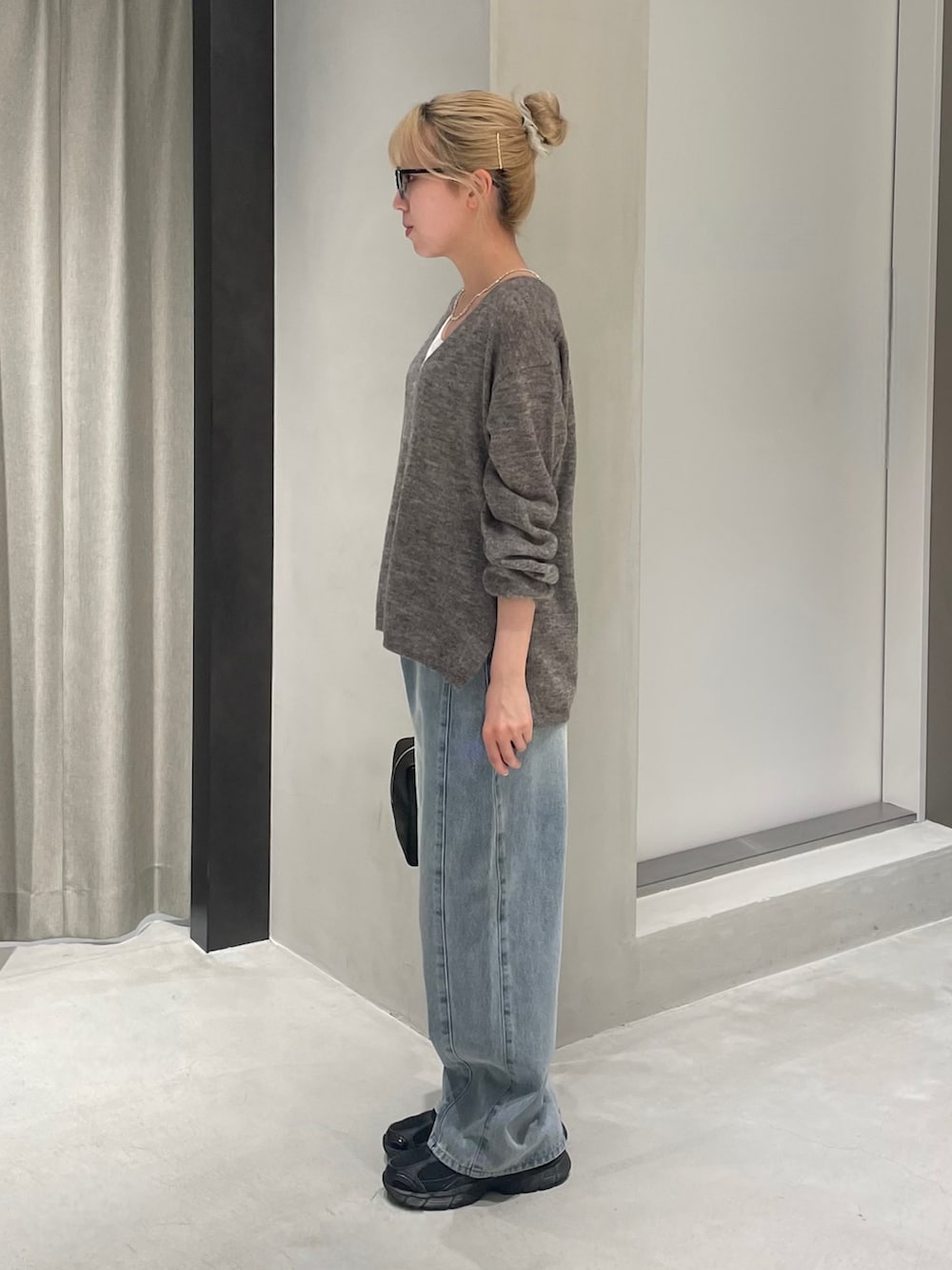 ブラック系のスニーカー、ブルー系のデニムパンツ、ホワイト系のタンクトップを着用したレディースの夏コーディネートの3枚目の写真