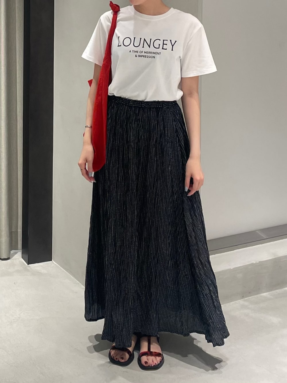 レッド系のショルダーバッグ、ブラック系のサンダル、ホワイト系のTシャツ/カットソーを着用したレディースの夏コーディネートの3枚目の写真