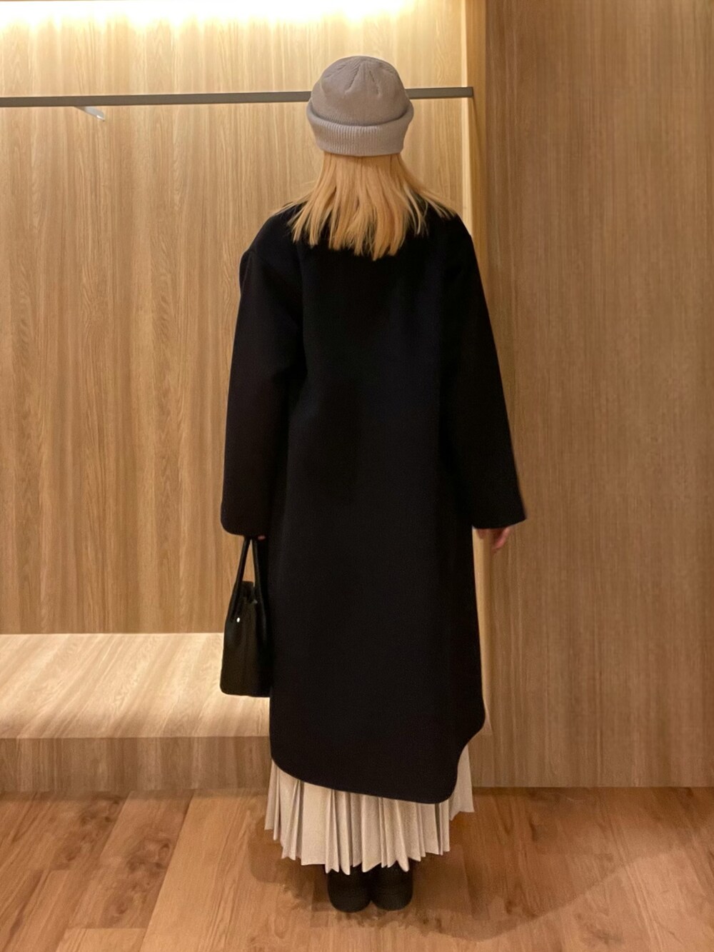 ブラック系のハンドバッグ、ブラック系のブーツ、ブルー系のその他アウターを着用したレディースの冬コーディネートの4枚目の写真