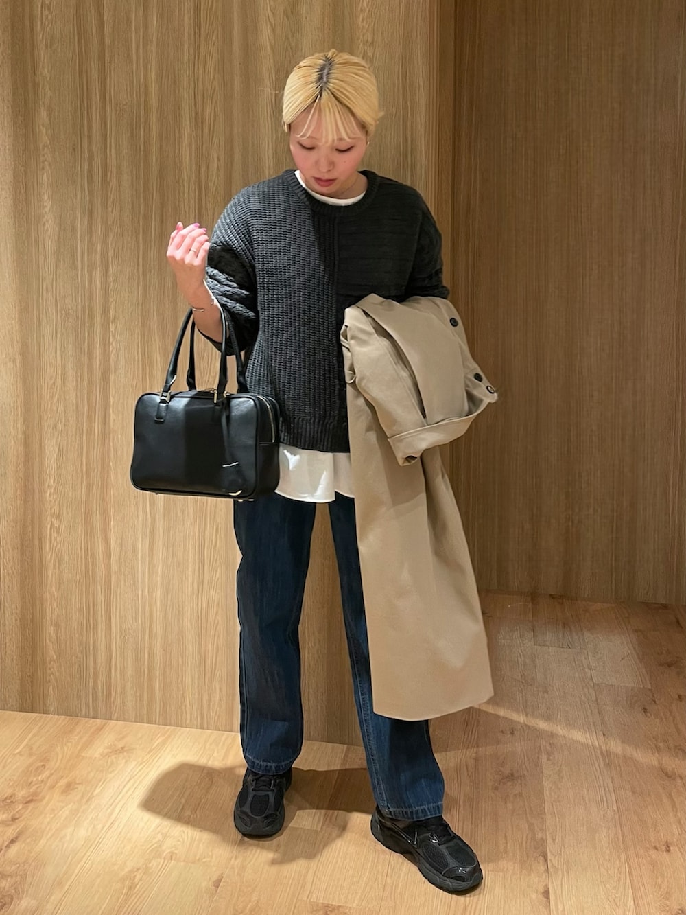 ブラック系のスニーカー、ブルー系のデニムパンツ、ブラック系のボストンバッグを着用したレディースの冬コーディネートの4枚目の写真