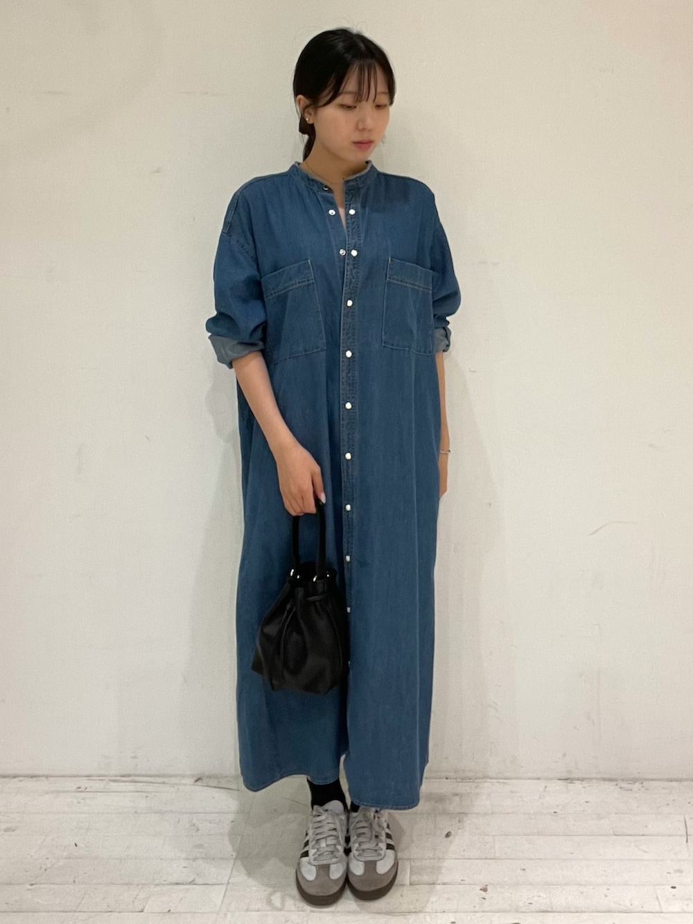 ブルー系のワンピース、ブラック系のショルダーバッグ、ホワイト系のスニーカーを着用したレディースの秋コーディネートの2枚目の写真