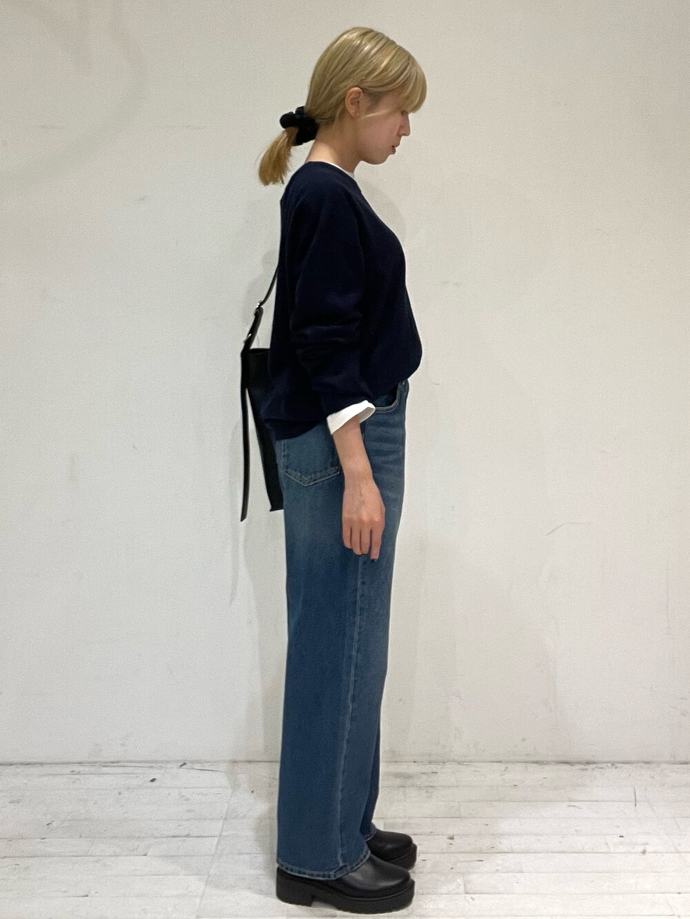 ブルー系のデニムパンツ、ブラック系のショルダーバッグ、ブラック系のブーツを着用したレディースの秋コーディネートの3枚目の写真