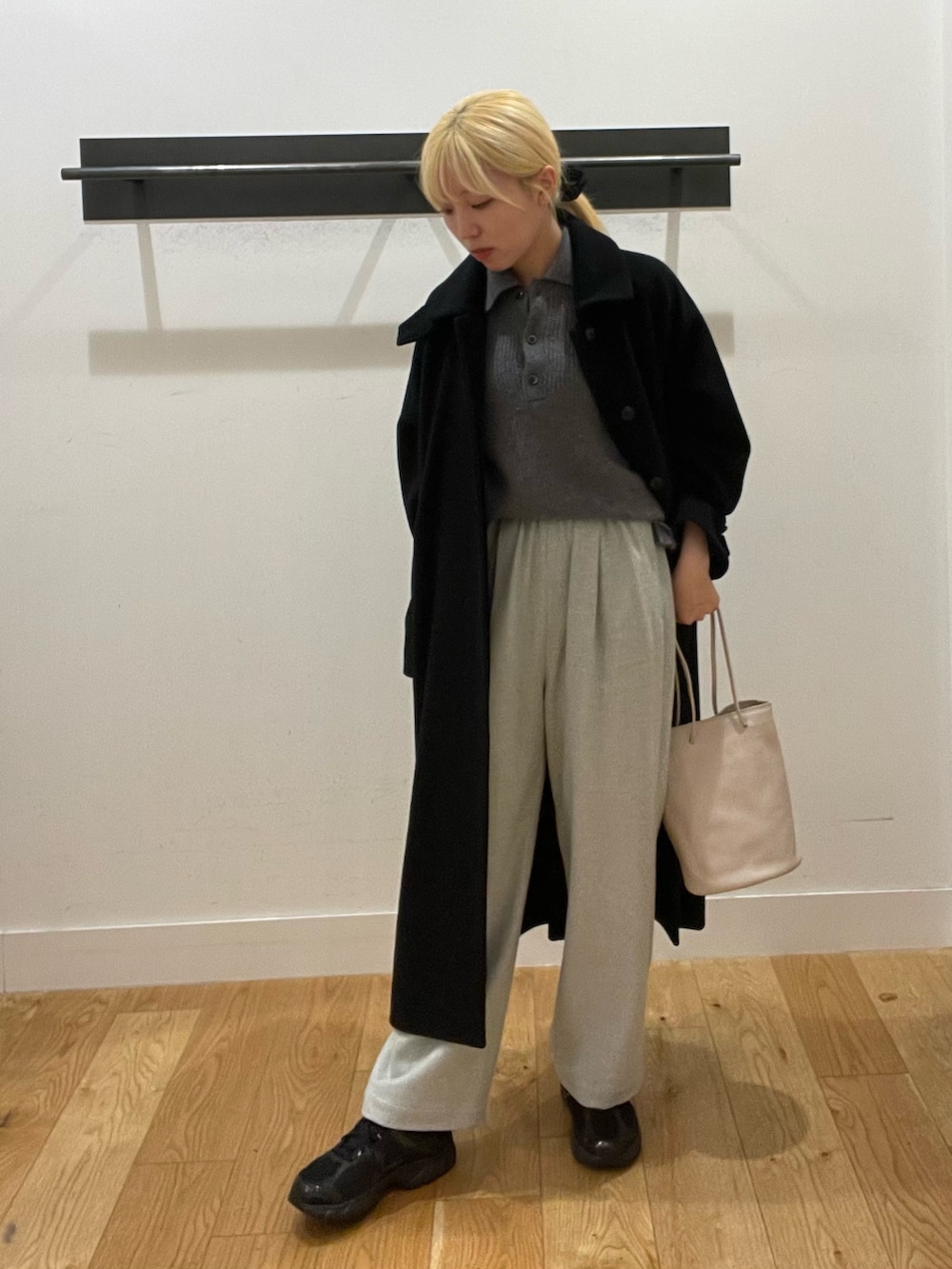 ブラック系のステンカラーコート、グレー系のニット/セーター、グレー系のその他パンツを着用したレディースの冬コーディネートの2枚目の写真