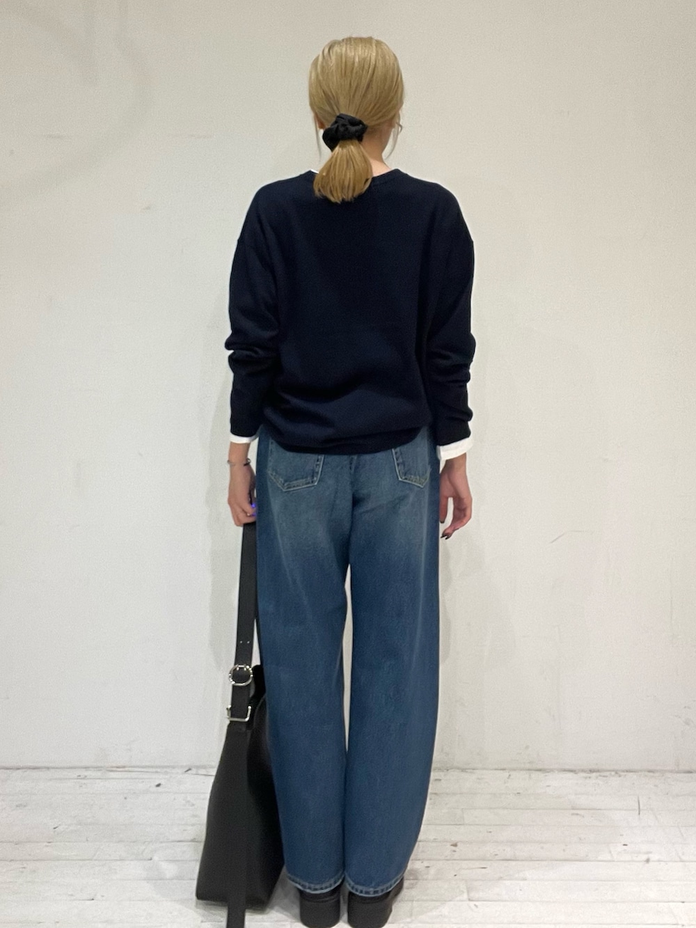 ブルー系のデニムパンツ、ブラック系のショルダーバッグ、ブラック系のブーツを着用したレディースの秋コーディネートの4枚目の写真