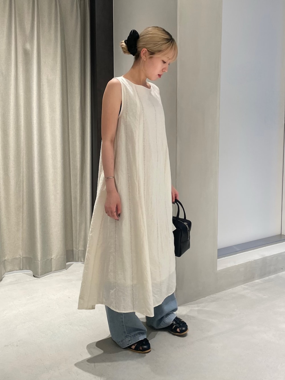 ブルー系のデニムパンツ、ブラック系のサンダル、ブラック系のボストンバッグを着用したレディースの夏コーディネートの3枚目の写真