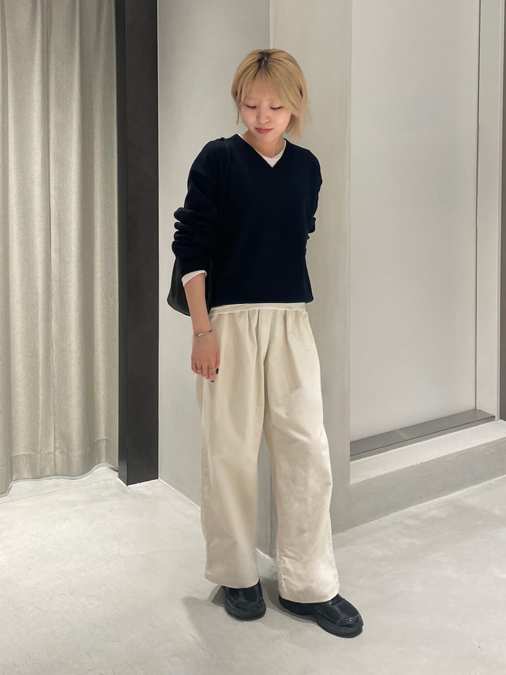 ブラック系のスニーカー、ブルー系のニット/セーター、ホワイト系のTシャツ/カットソーを着用したレディースの秋コーディネートの2枚目の写真