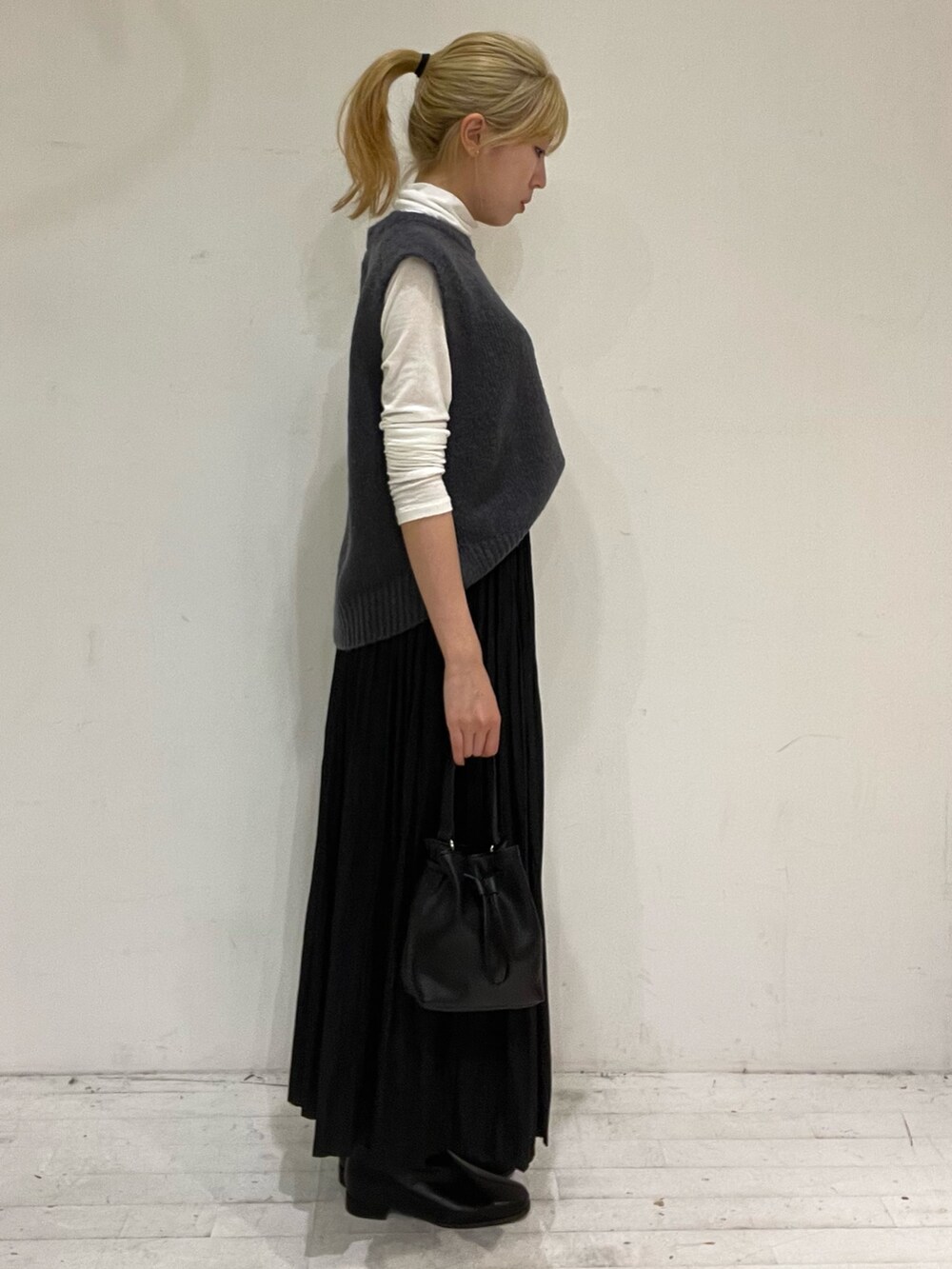 ブラック系のスカート、ブラック系のショルダーバッグ、ブラック系のブーツを着用したレディースの秋コーディネートの3枚目の写真