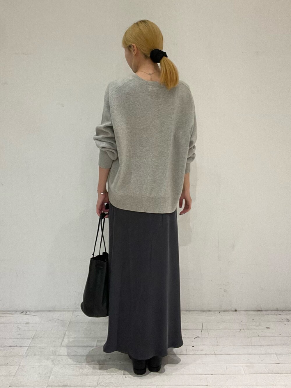 グレー系のスカート、ブラック系のブーツ、ブラック系のショルダーバッグを着用したレディースの秋コーディネートの4枚目の写真