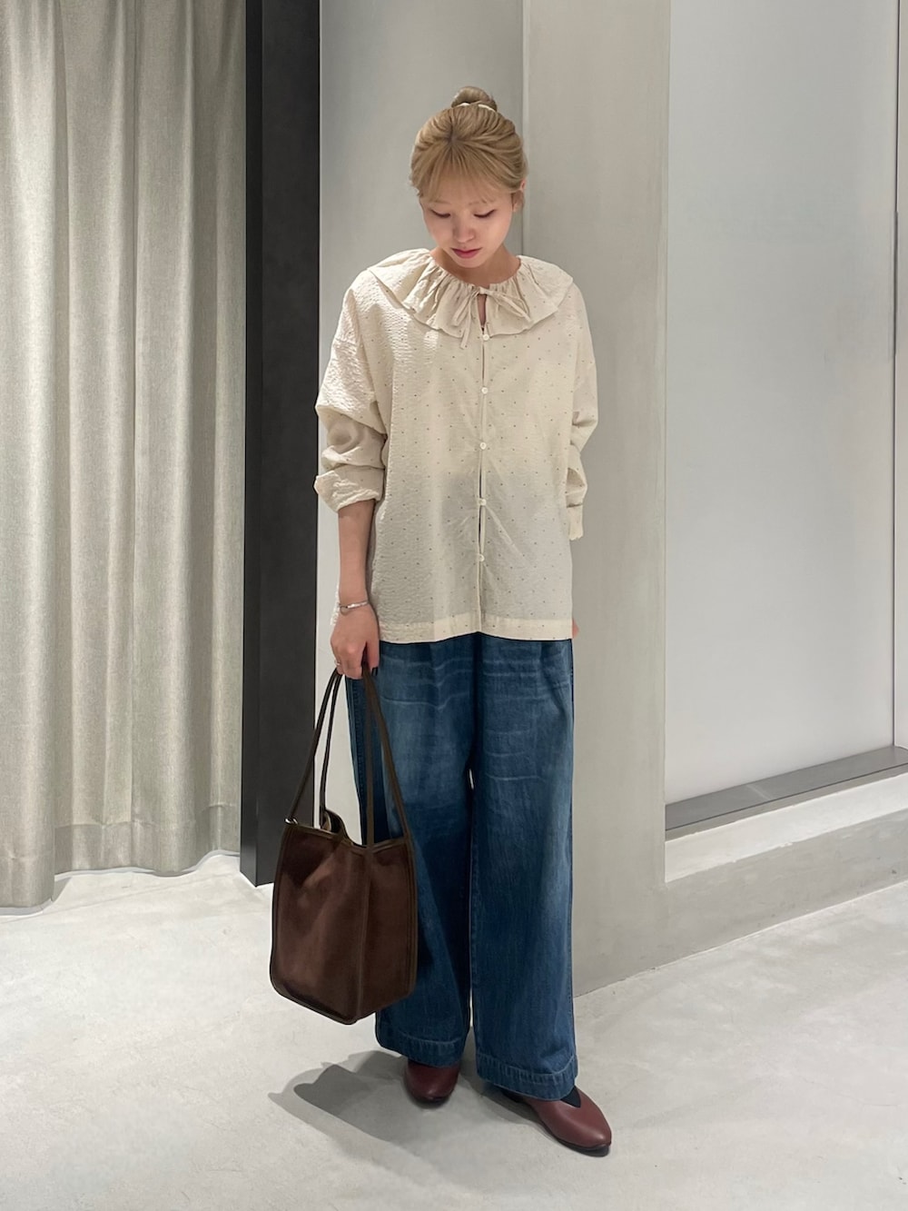 ブラウン系のパンプス、ブラウン系のトートバッグ、ブルー系のデニムパンツを着用したレディースの秋コーディネートの2枚目の写真