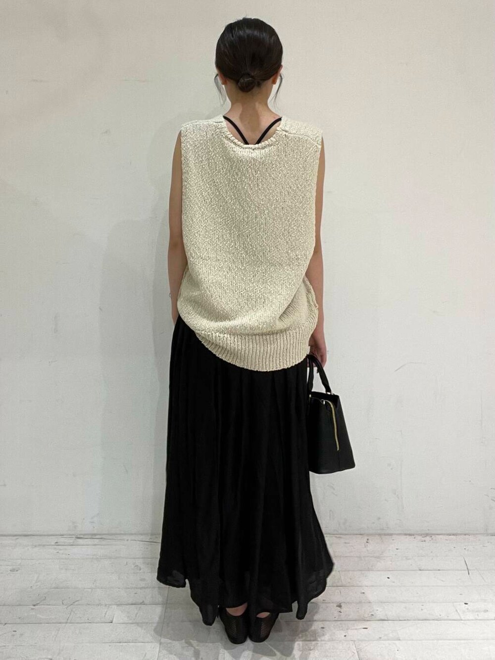 ブラック系のハンドバッグ、ブラック系のバレエシューズ、ベージュ系のベストを着用したレディースの夏コーディネートの4枚目の写真