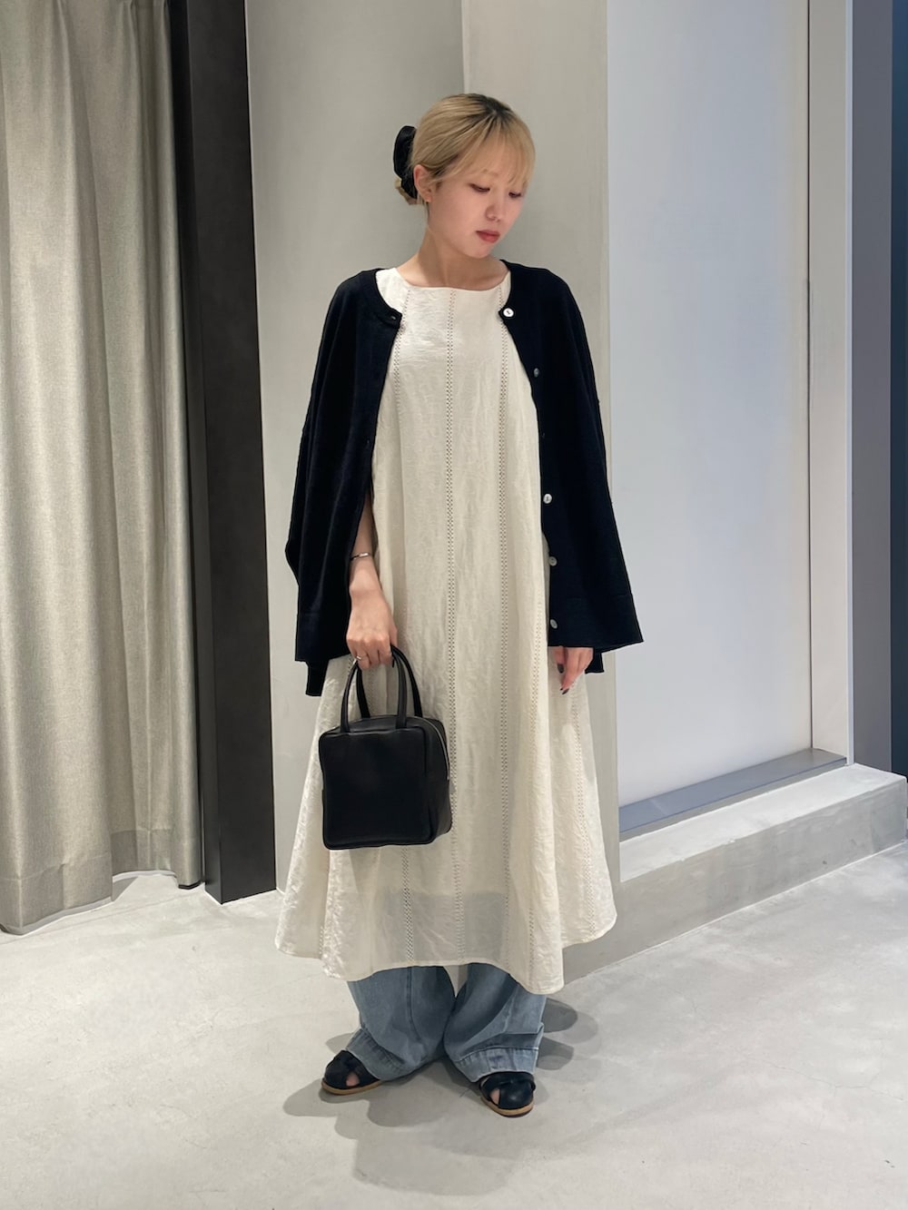 ブルー系のデニムパンツ、ブラック系のサンダル、ブラック系のボストンバッグを着用したレディースの夏コーディネートの2枚目の写真