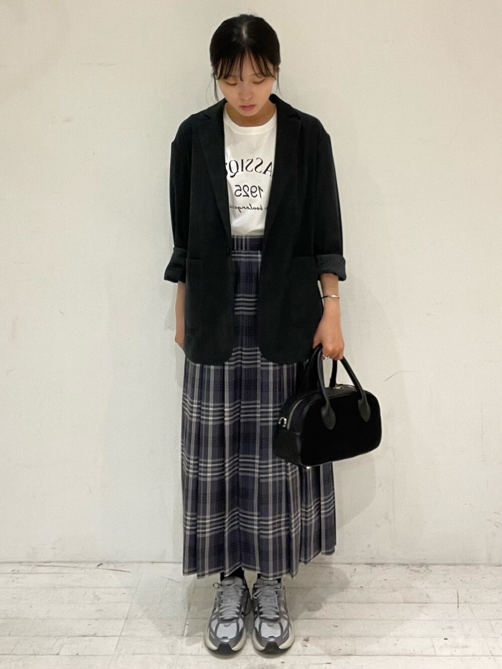 グレー系のスカート、ブラック系のショルダーバッグ、ホワイト系のTシャツ/カットソーを着用したレディースの秋コーディネートの2枚目の写真