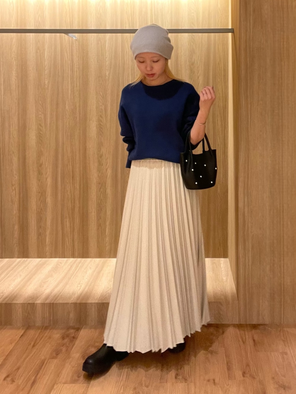 ブラック系のハンドバッグ、ブラック系のブーツ、ブルー系のその他アウターを着用したレディースの冬コーディネートの2枚目の写真