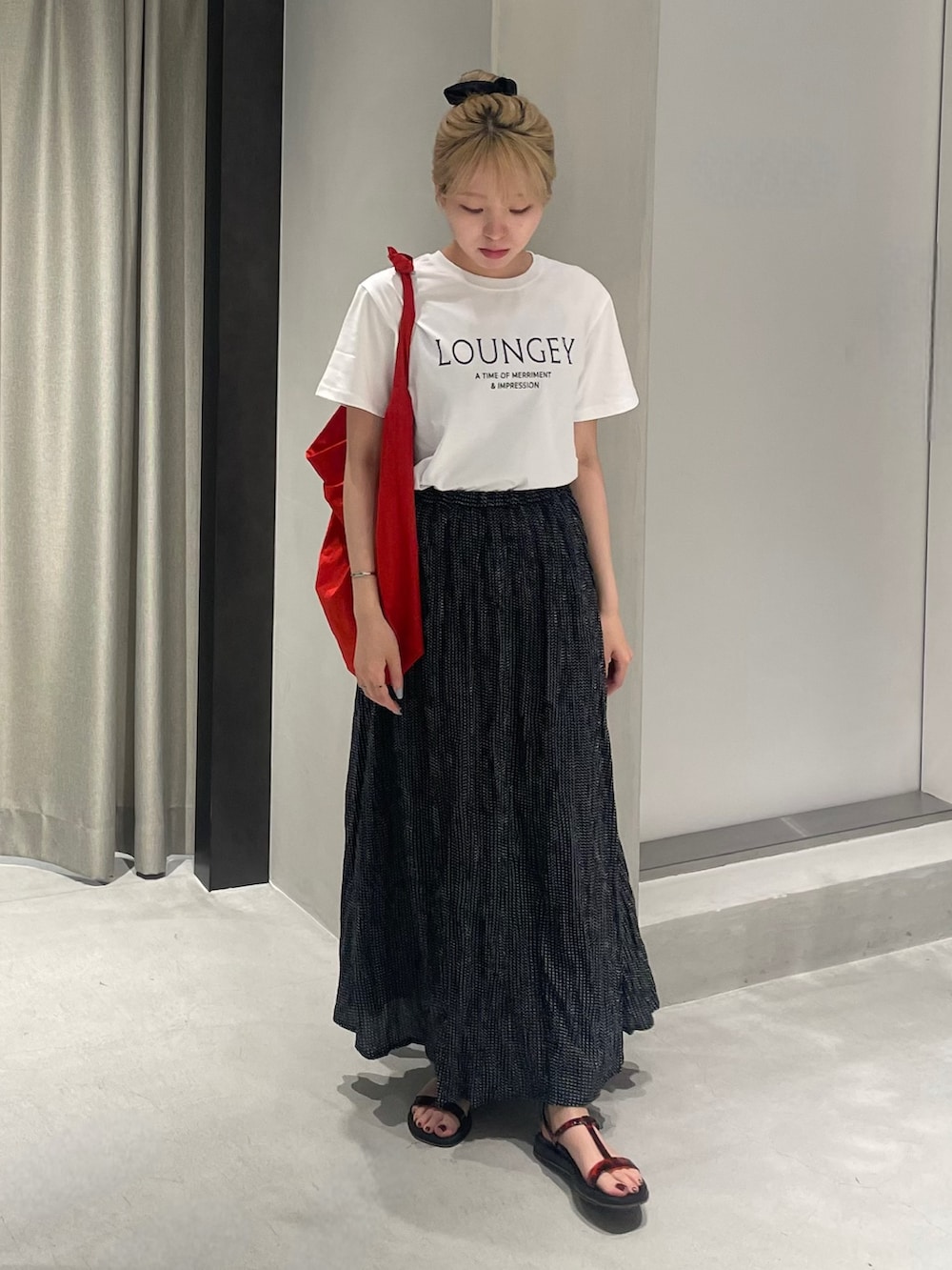 レッド系のショルダーバッグ、ブラック系のサンダル、ホワイト系のTシャツ/カットソーを着用したレディースの夏コーディネートの2枚目の写真