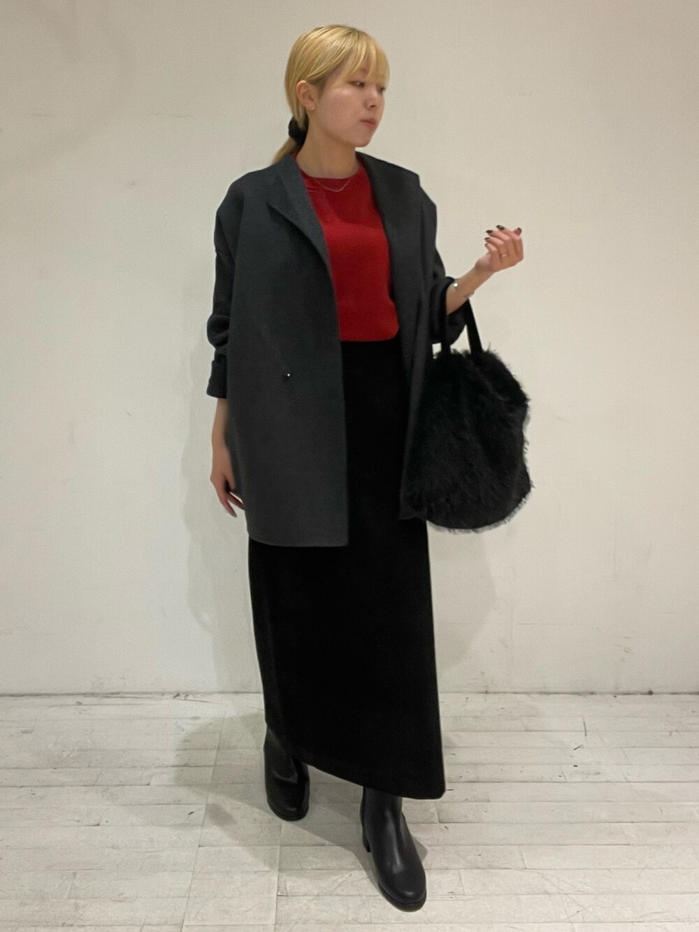 レッド系のニット/セーター、グレー系のその他アウター、ブラック系のスカートを着用したレディースの秋コーディネートの2枚目の写真