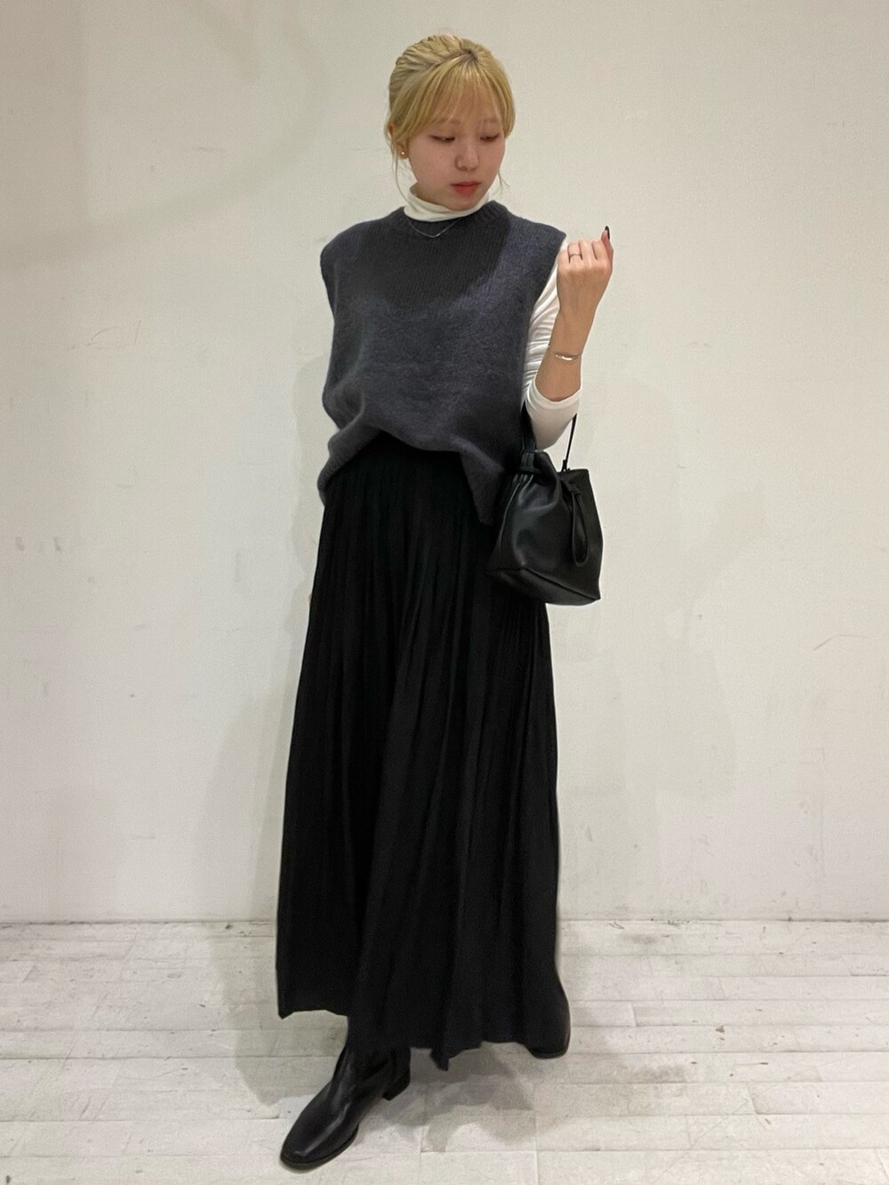 ブラック系のスカート、ブラック系のショルダーバッグ、ブラック系のブーツを着用したレディースの秋コーディネートの2枚目の写真