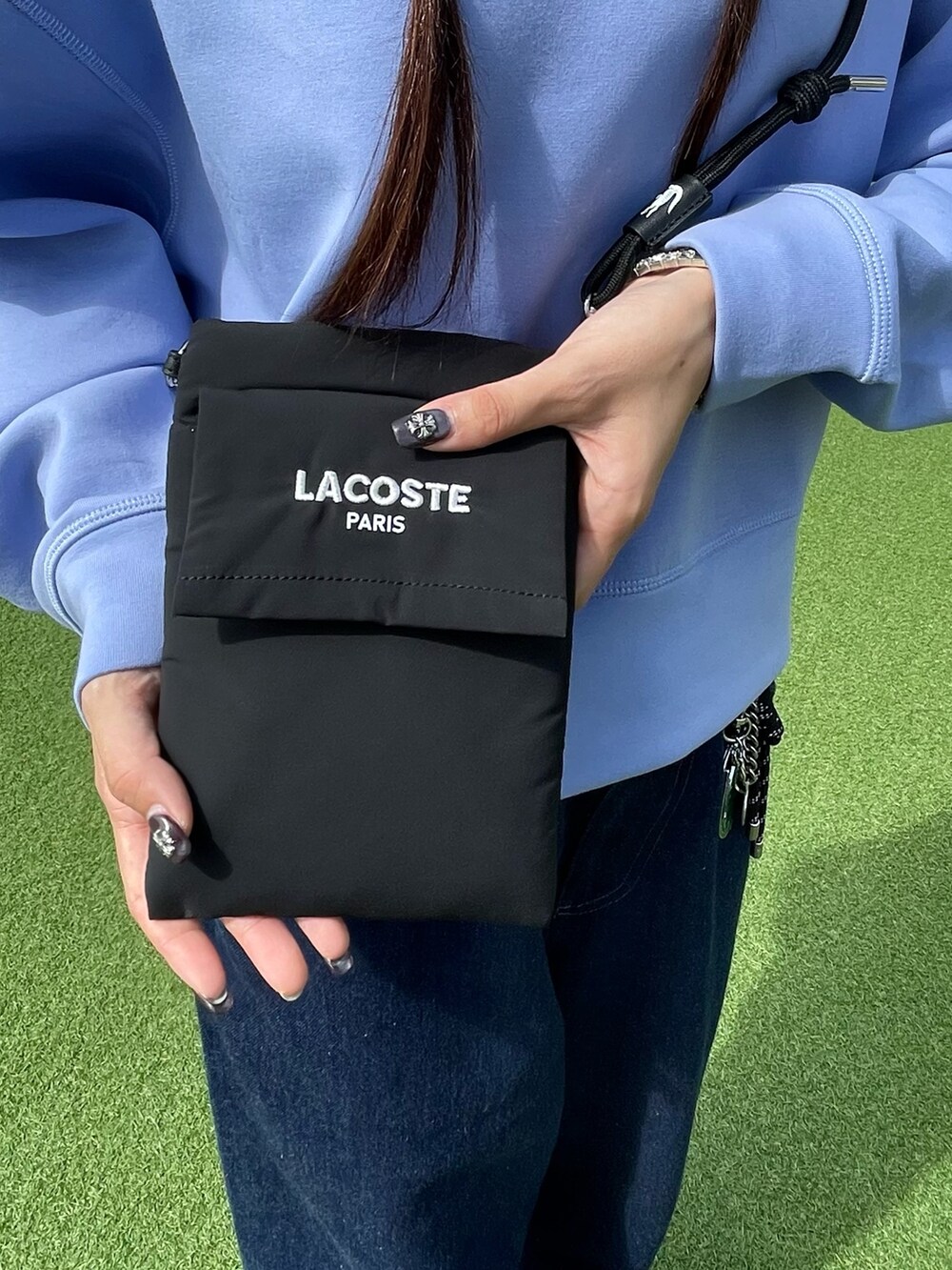 レッド系のスニーカー、ブラック系のショルダーバッグ、ブルー系のデニムパンツを着用したレディースの秋コーディネートの7枚目の写真