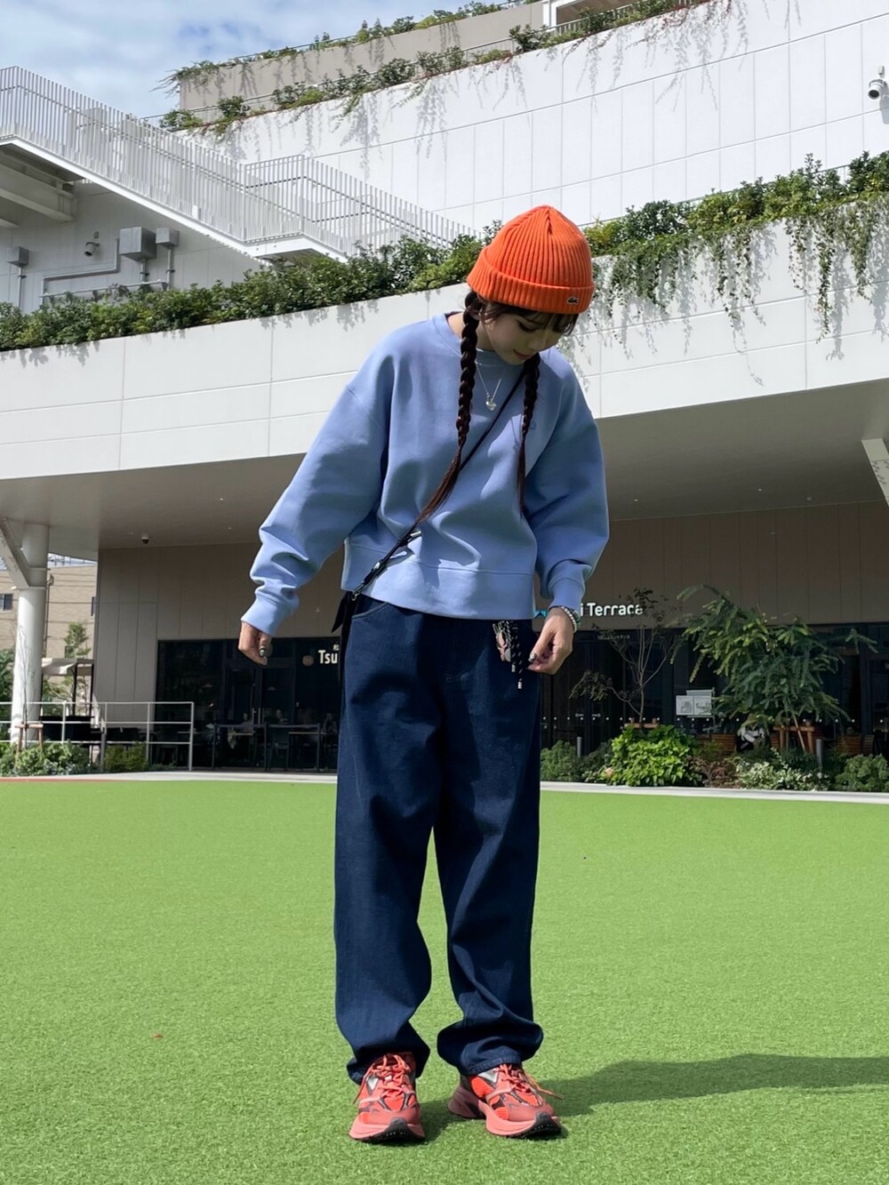 レッド系のスニーカー、ブラック系のショルダーバッグ、ブルー系のデニムパンツを着用したレディースの秋コーディネートの2枚目の写真