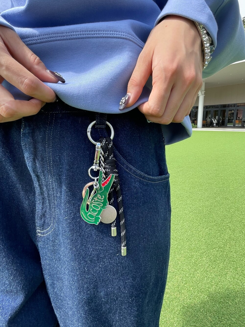 レッド系のスニーカー、ブラック系のショルダーバッグ、ブルー系のデニムパンツを着用したレディースの秋コーディネートの8枚目の写真