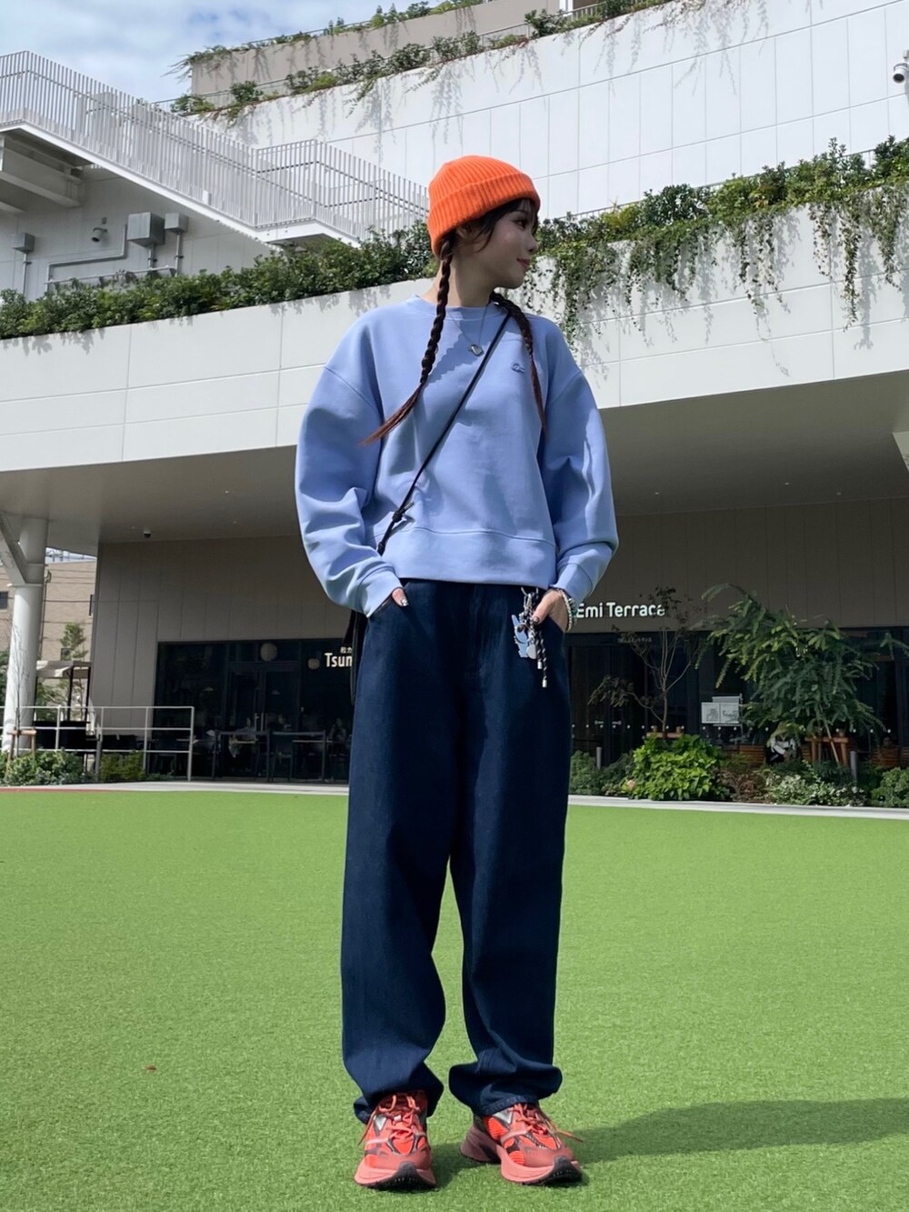 レッド系のスニーカー、ブラック系のショルダーバッグ、ブルー系のデニムパンツを着用したレディースの秋コーディネートの3枚目の写真