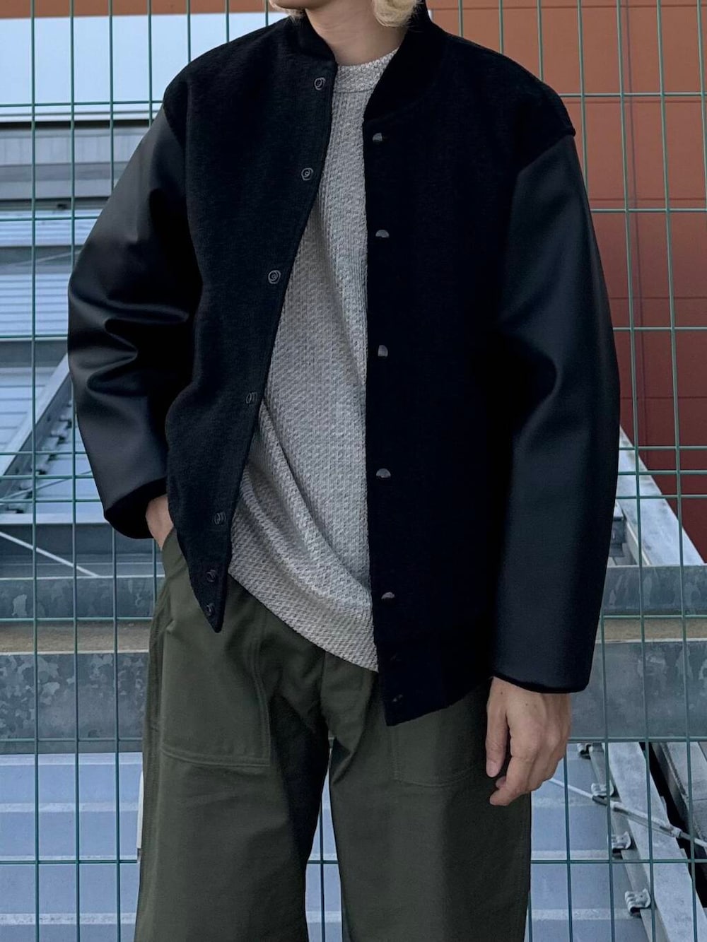 ベージュ系のTシャツ/カットソー、ホワイト系のスニーカー、ブラック系のスタジャンを着用したメンズの秋コーディネートの3枚目の写真