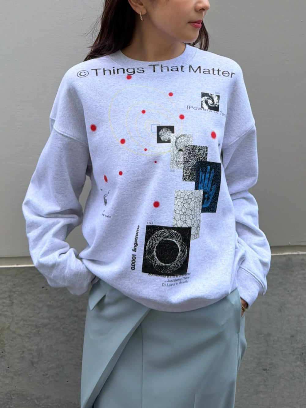 グレー系のスウェット、ブルー系のスカートを着用したレディースの秋コーディネートの2枚目の写真