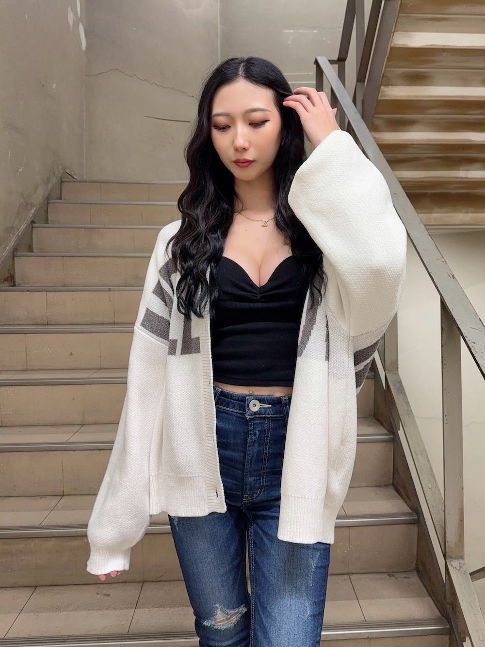 ブルー系のデニムパンツ、ブラック系のキャミソール、ホワイト系のカーディガン/ボレロを着用したレディースの冬コーディネートの4枚目の写真