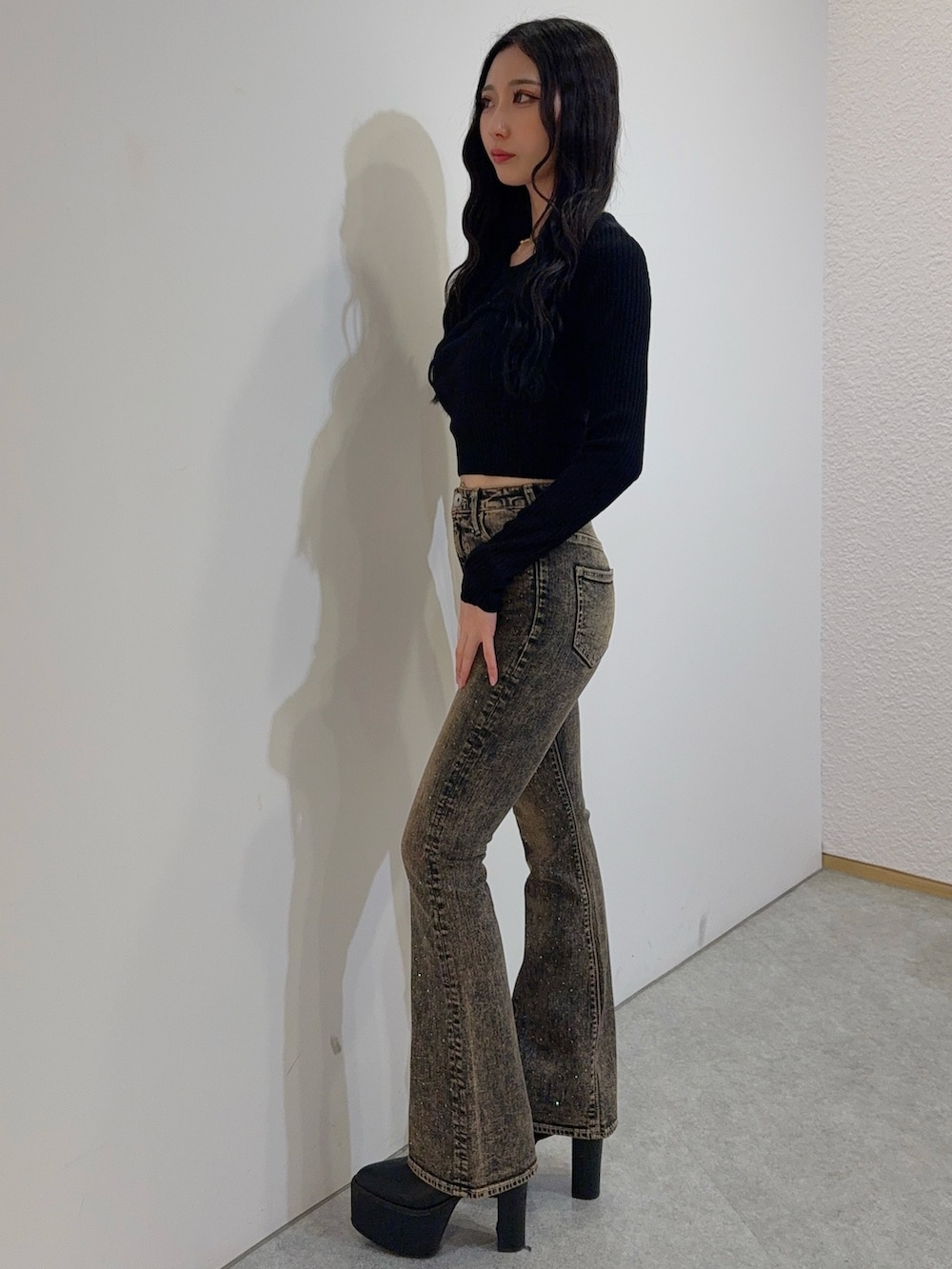 ブルー系のデニムパンツ、ブラック系のニット/セーター、ブラック系のブーツを着用したレディースの冬コーディネートの2枚目の写真