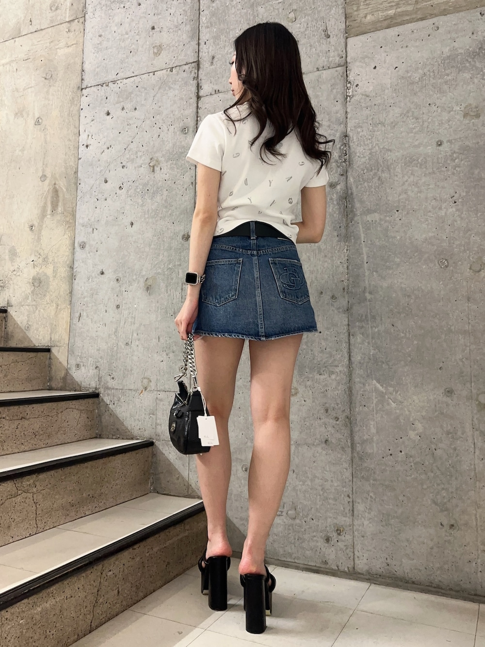 ブルー系のデニムスカート、ホワイト系のTシャツ/カットソー、ブラック系のサンダルを着用したレディースの春コーディネートの3枚目の写真