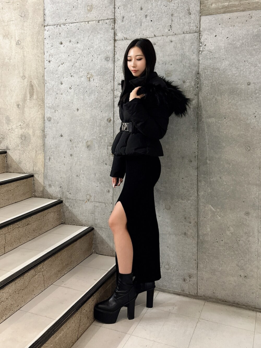 ブラック系のブーツ、ブラック系のダウンジャケット/コート、ブラック系のワンピースを着用したレディースの秋コーディネートの2枚目の写真