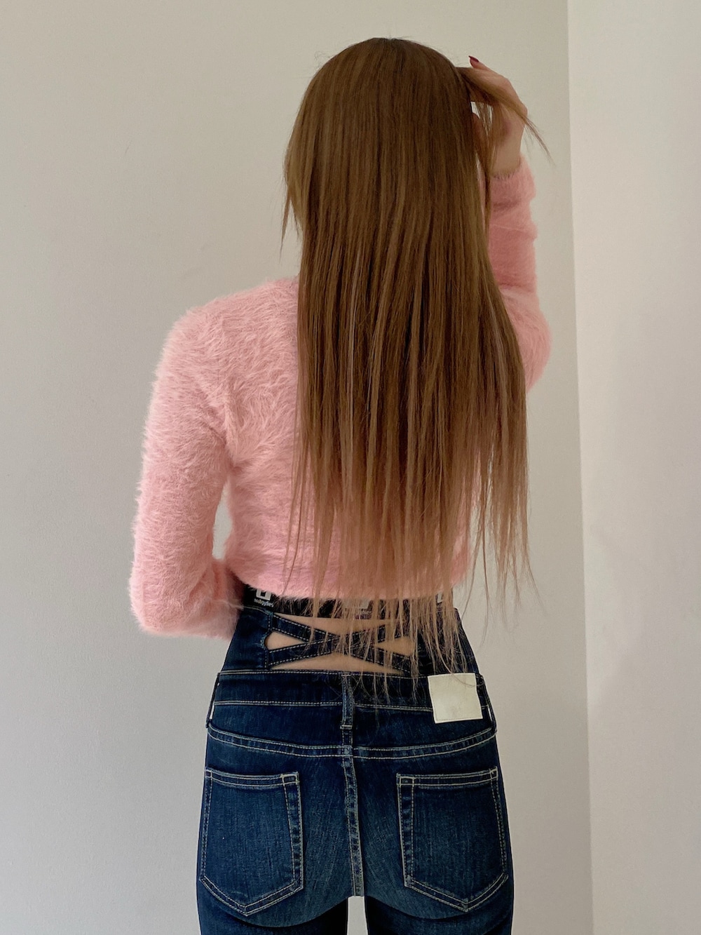 ピンク系のニット/セーター、ブルー系のデニムパンツ、ブラック系のブーツを着用したレディースの冬コーディネートの5枚目の写真