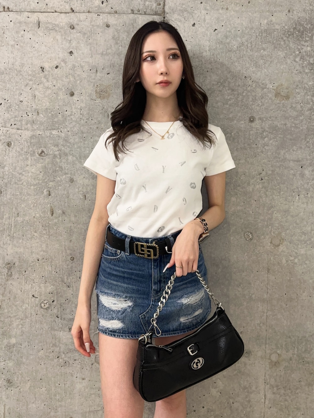 ブルー系のデニムスカート、ホワイト系のTシャツ/カットソー、ブラック系のサンダルを着用したレディースの春コーディネートの4枚目の写真