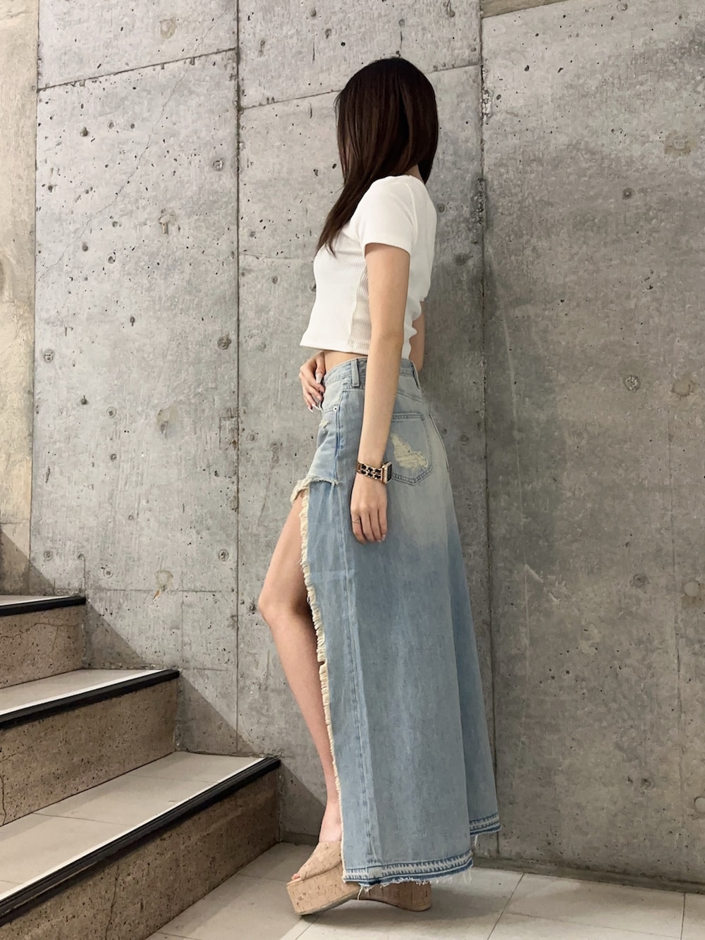 ブルー系のデニムスカート、ホワイト系のサンダル、ホワイト系のTシャツ/カットソーを着用したレディースの春コーディネートの2枚目の写真