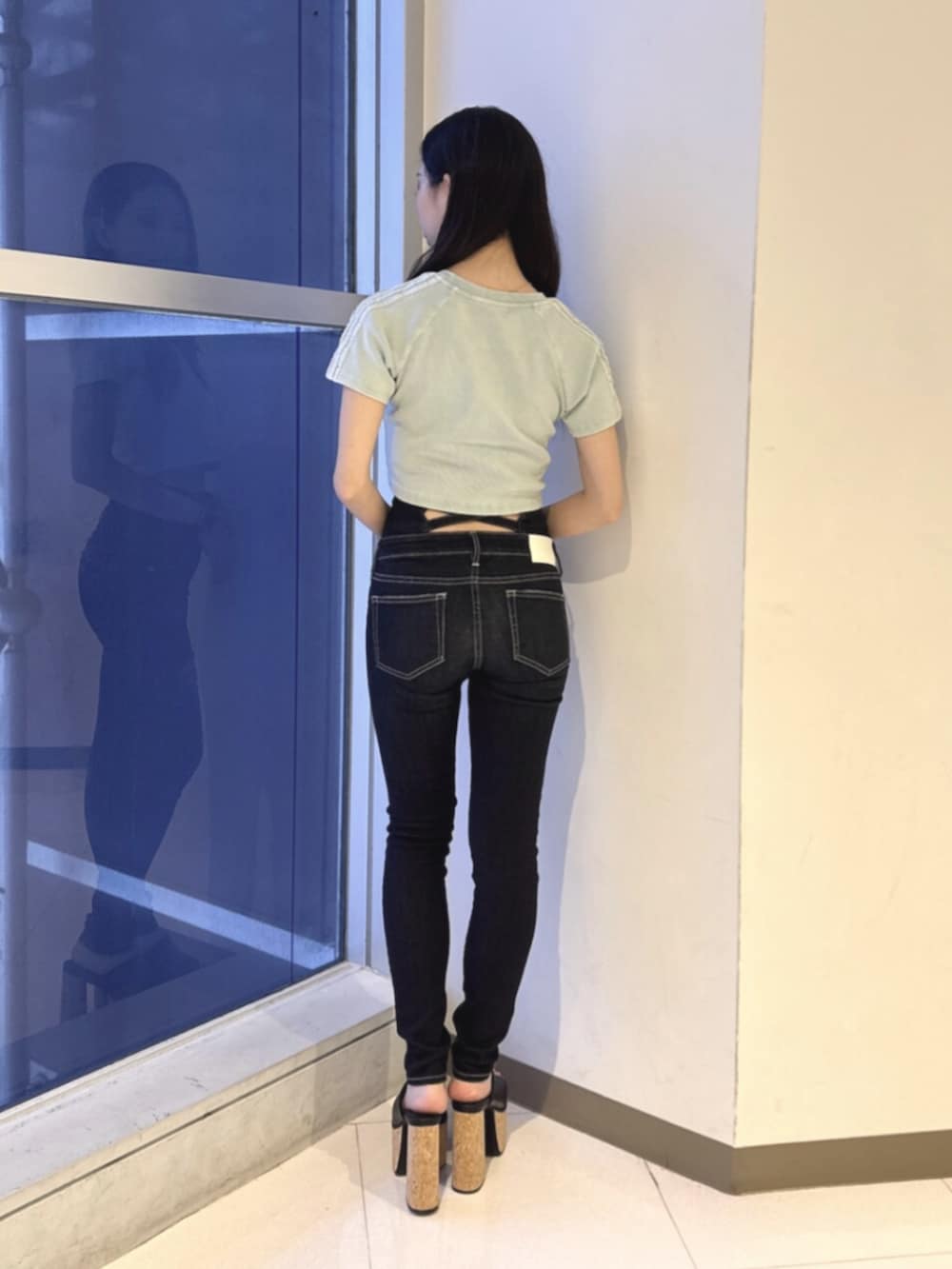 ブルー系のデニムパンツ、ブラック系のサンダル、ブルー系のTシャツ/カットソーを着用したレディースの夏コーディネートの3枚目の写真