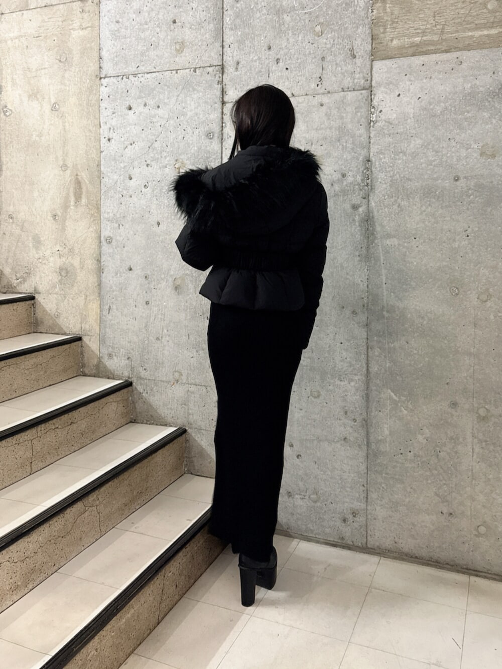 ブラック系のブーツ、ブラック系のダウンジャケット/コート、ブラック系のワンピースを着用したレディースの秋コーディネートの3枚目の写真