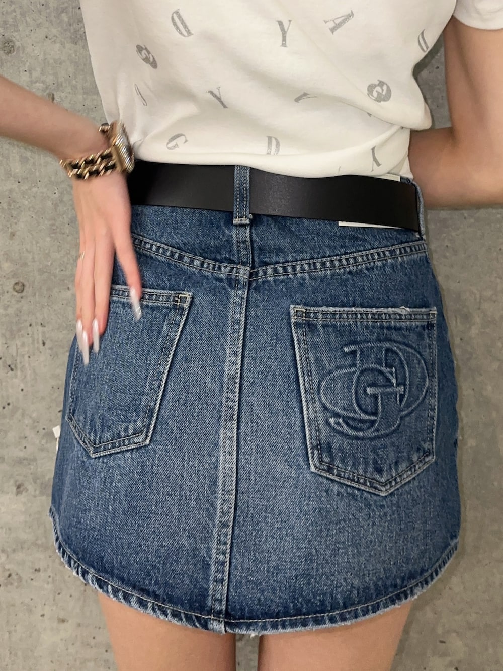 ブルー系のデニムスカート、ホワイト系のTシャツ/カットソー、ブラック系のサンダルを着用したレディースの春コーディネートの6枚目の写真