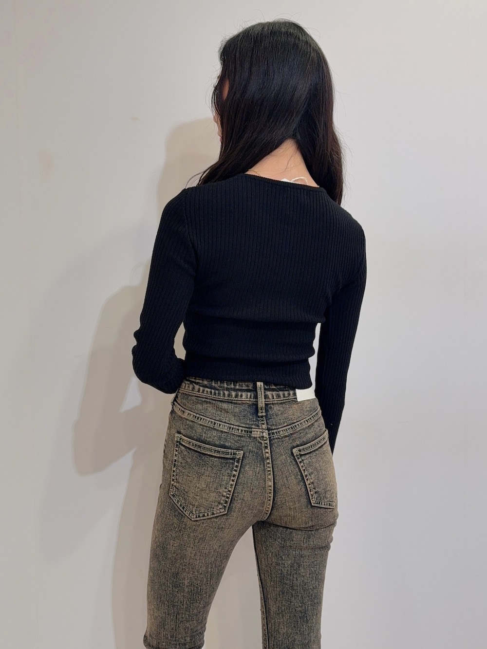 ブルー系のデニムパンツ、ブラック系のニット/セーター、ブラック系のブーツを着用したレディースの冬コーディネートの4枚目の写真