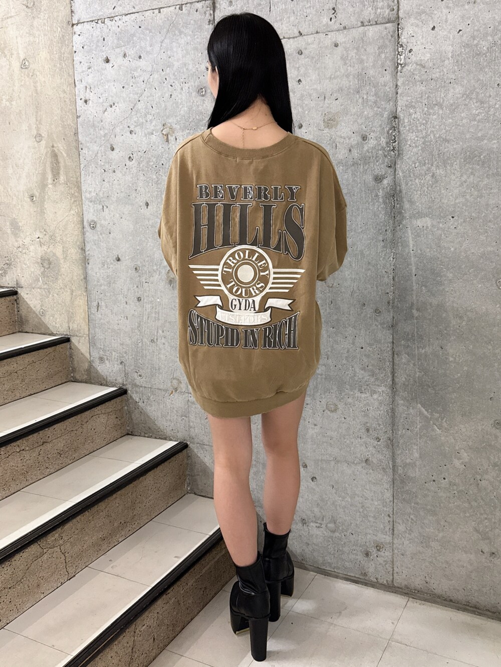 イエロー系のスウェット、ブラック系のブーツ、ブラック系のデニムスカートを着用したレディースの夏コーディネートの3枚目の写真