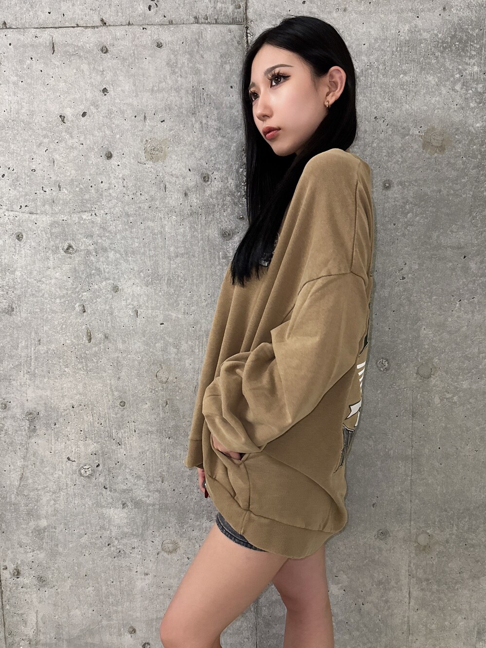 イエロー系のスウェット、ブラック系のブーツ、ブラック系のデニムスカートを着用したレディースの夏コーディネートの5枚目の写真