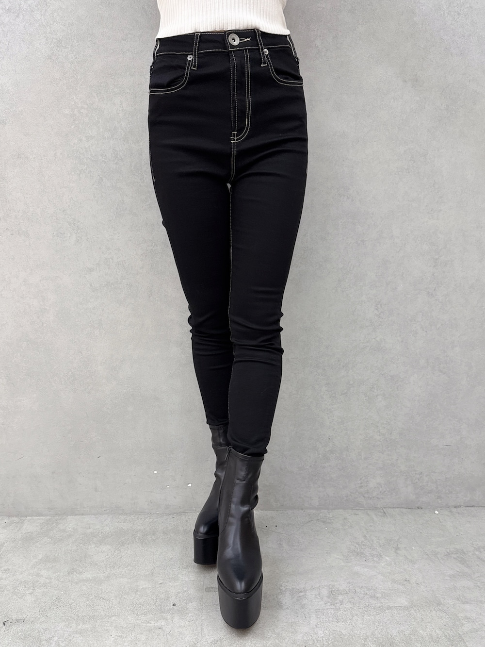 ブラック系のデニムパンツ、ブラック系のブーツ、ホワイト系のニット/セーターを着用したレディースの秋コーディネートの5枚目の写真