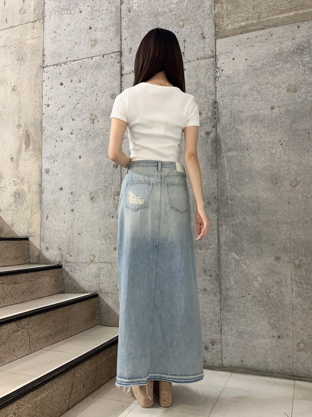 ブルー系のデニムスカート、ホワイト系のサンダル、ホワイト系のTシャツ/カットソーを着用したレディースの春コーディネートの3枚目の写真