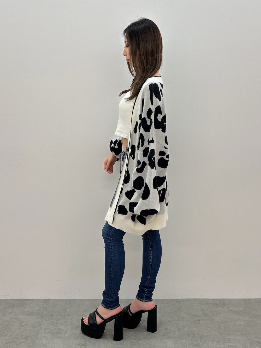 ブルー系のデニムパンツ、ブラック系のサンダル、ホワイト系のカーディガン/ボレロを着用したレディースの夏コーディネートの2枚目の写真