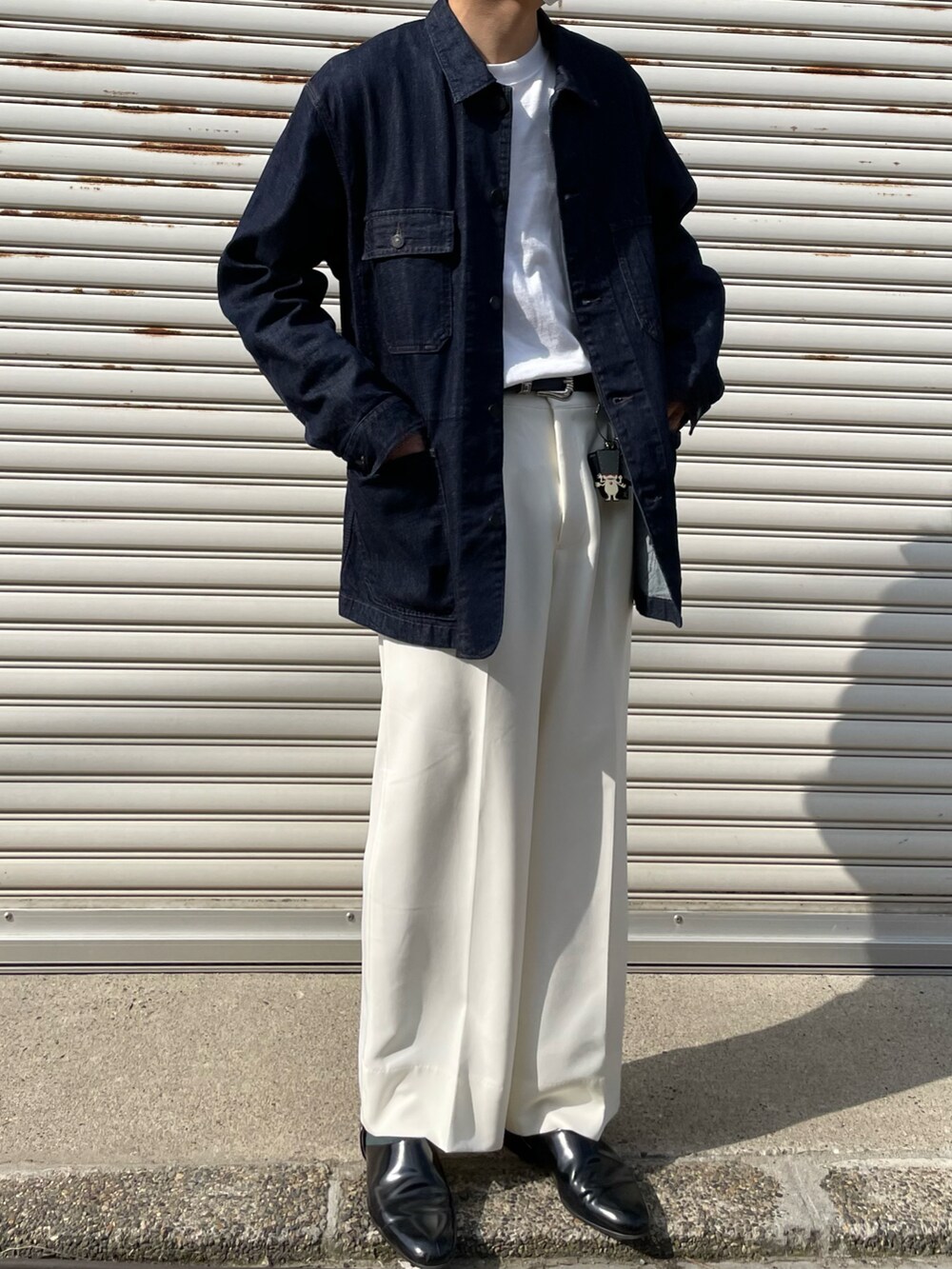 ブラック系のデニムジャケット、ホワイト系のスラックス、ブラック系のスリッポンを着用したメンズの春コーディネートの2枚目の写真