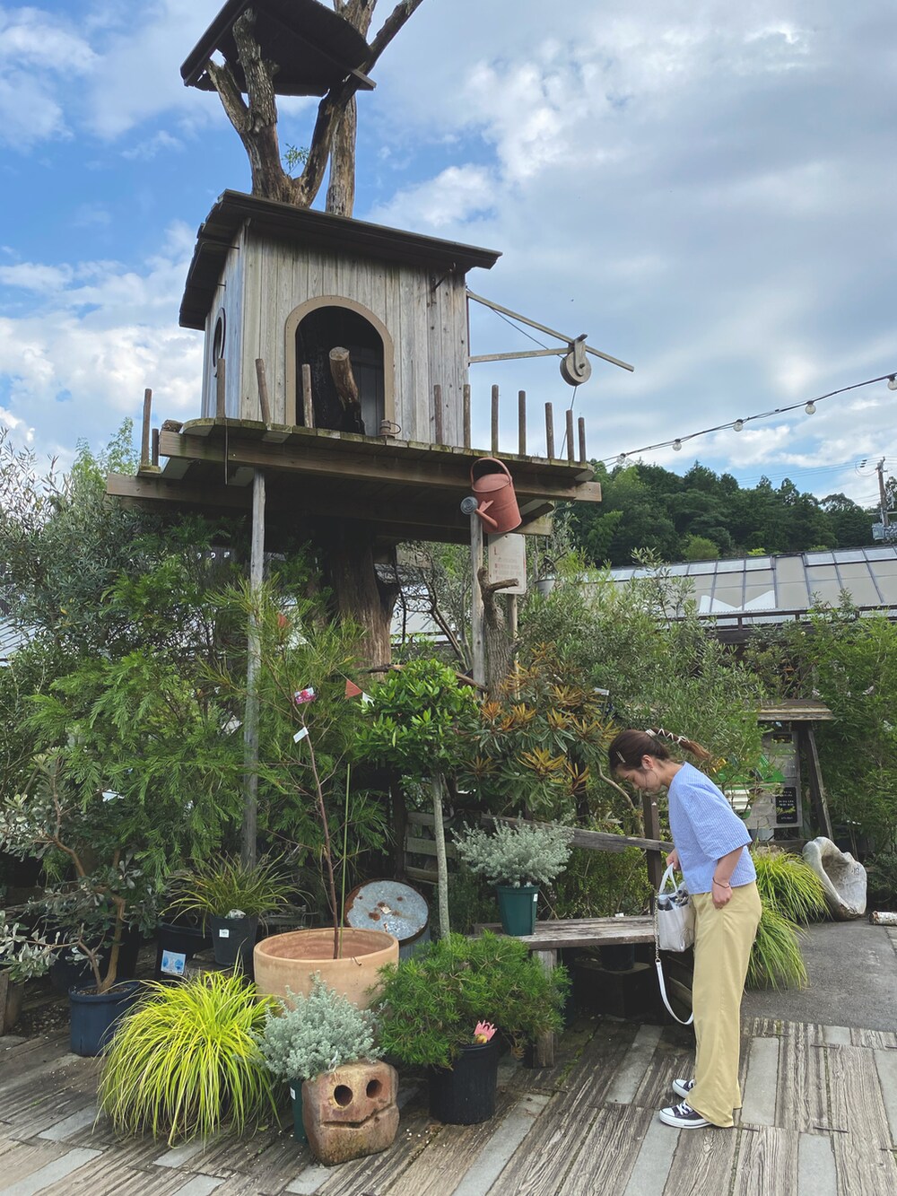 ブルー系のシャツ/ブラウス、イエロー系のスラックス、ブラック系のスニーカーを着用したレディースの夏コーディネートの2枚目の写真