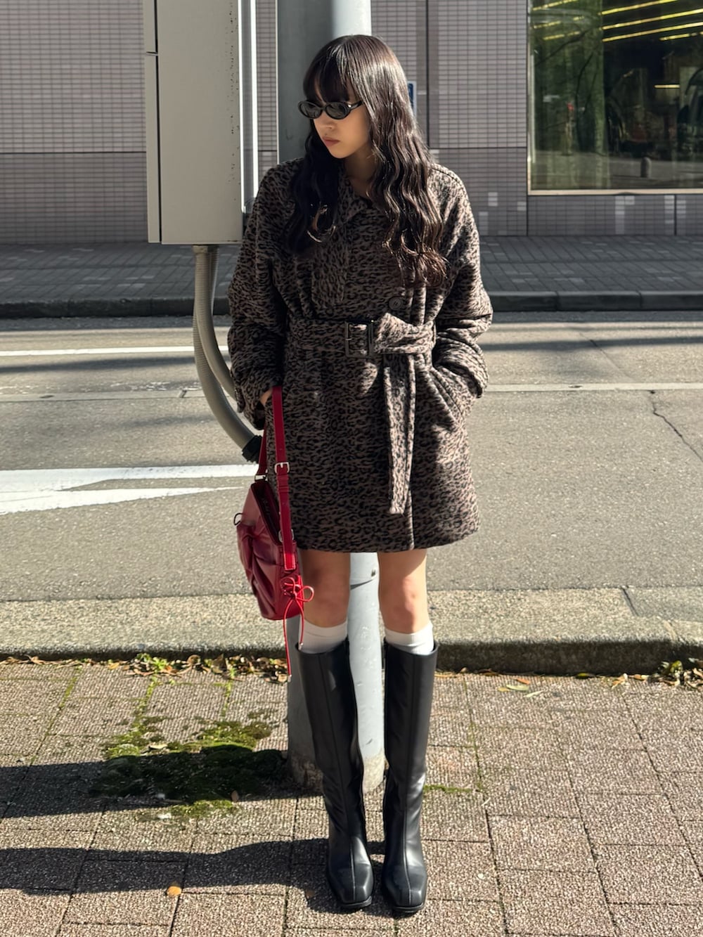 その他のステンカラーコート、レッド系のハンドバッグ、ブラック系のブーツを着用したレディースの秋コーディネートの2枚目の写真