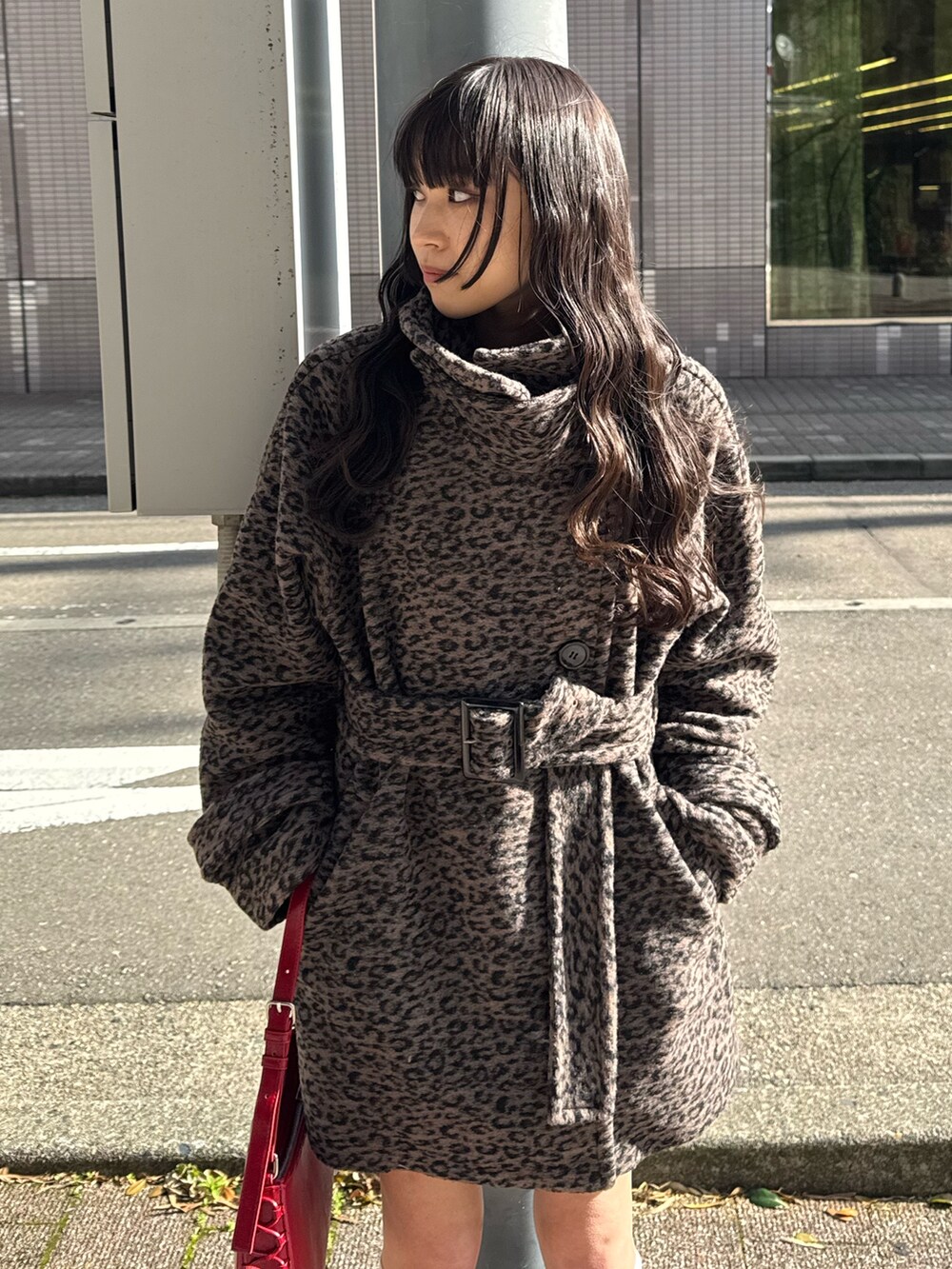 その他のステンカラーコート、レッド系のハンドバッグ、ブラック系のブーツを着用したレディースの秋コーディネートの3枚目の写真