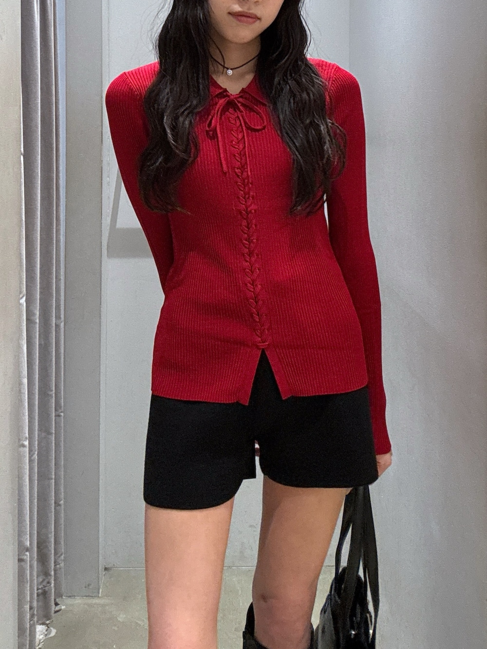 レッド系のニット/セーター、ブラック系のスラックス、ブラック系のショルダーバッグを着用したレディースの秋コーディネートの2枚目の写真