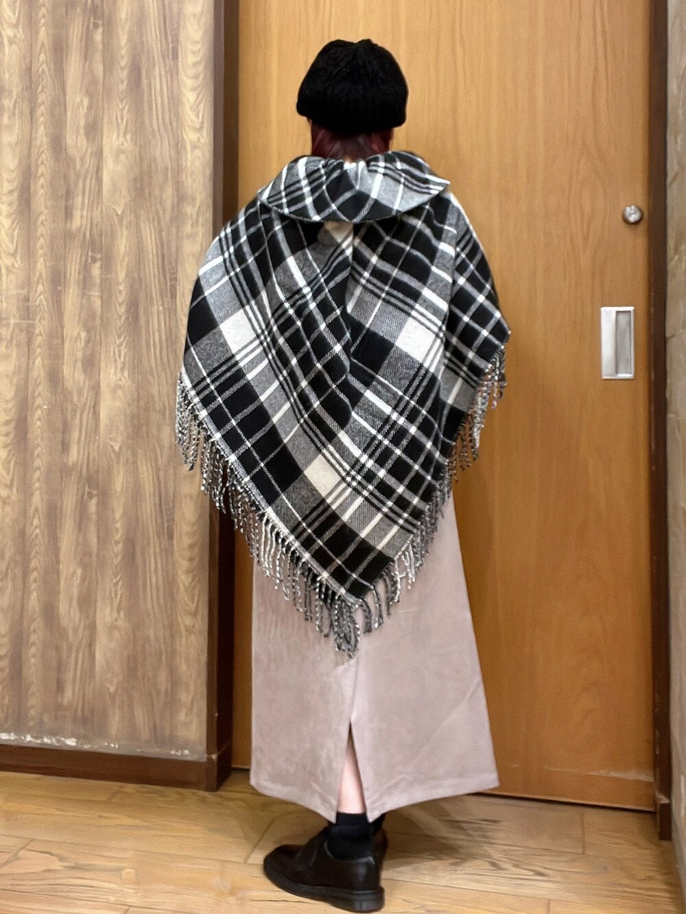 ブラウン系のTシャツ/カットソー、ベージュ系のスカート、ブラック系のポンチョを着用したレディースの秋コーディネートの2枚目の写真