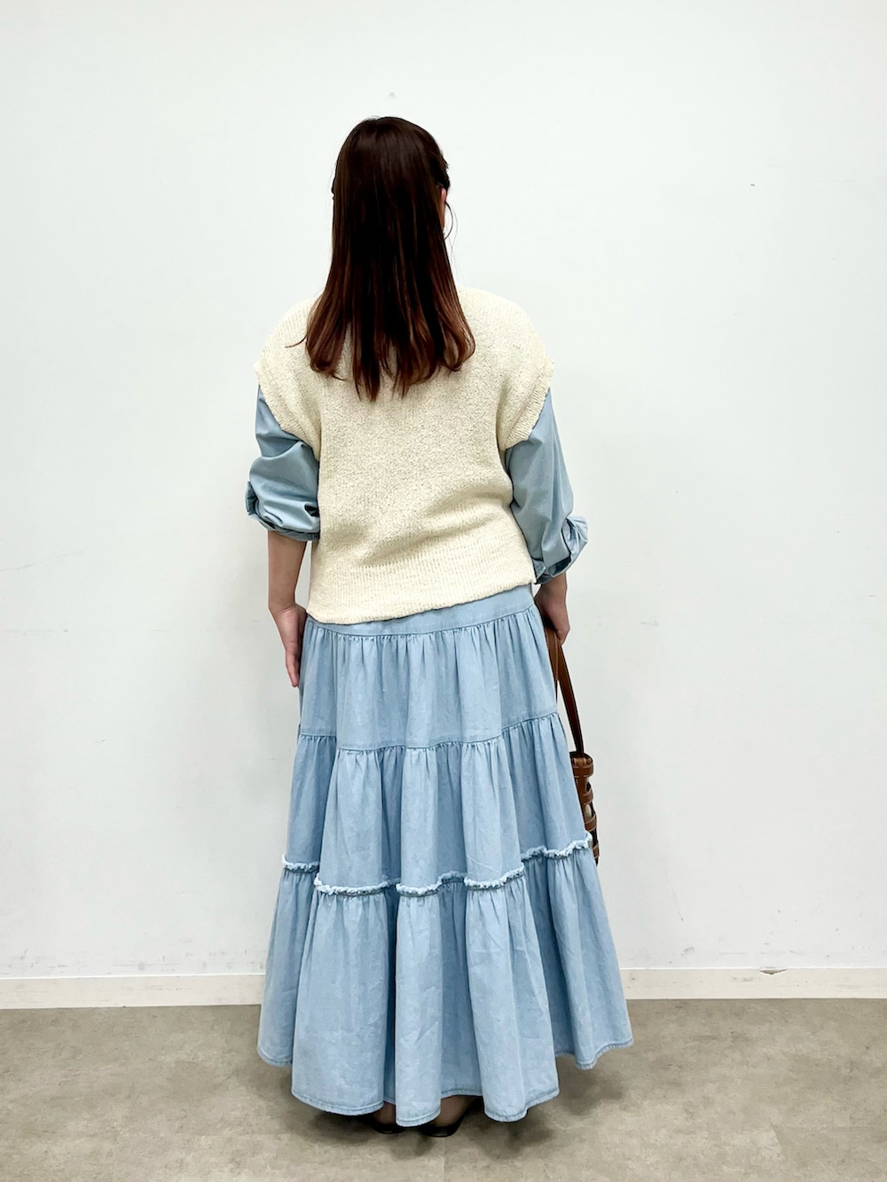 ホワイト系のベスト、ブルー系のシャツ/ブラウス、ブルー系のデニムスカートを着用したレディースの春コーディネートの2枚目の写真